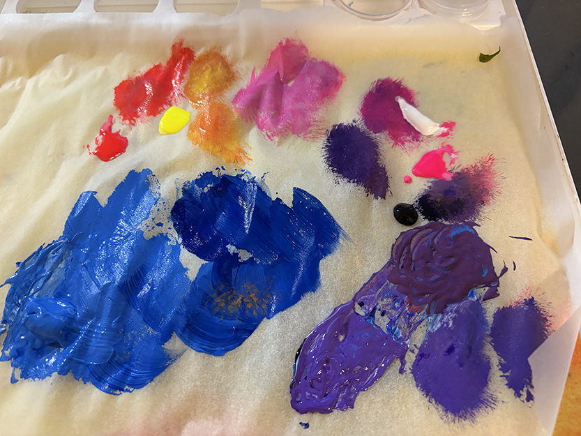 Artist’s paint palette featuring bright and neon acrylic gouache colors used in the making of the latest painting.