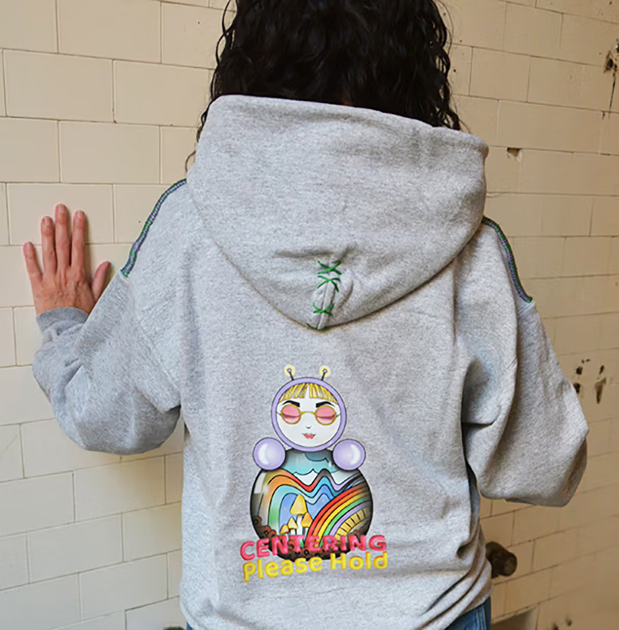 Back view of the gray “Centering Please Hold” sweatshirt featuring character O and a rainbow heart design.