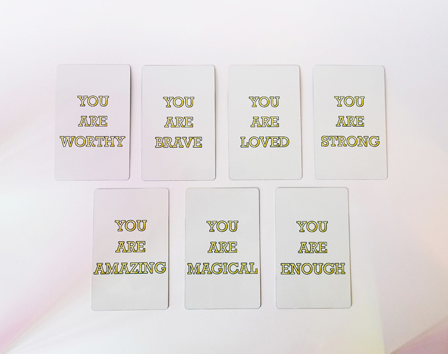 Set of affirmation cards with gold text messages like “You are worthy,” “You are brave,” and “You are loved.”