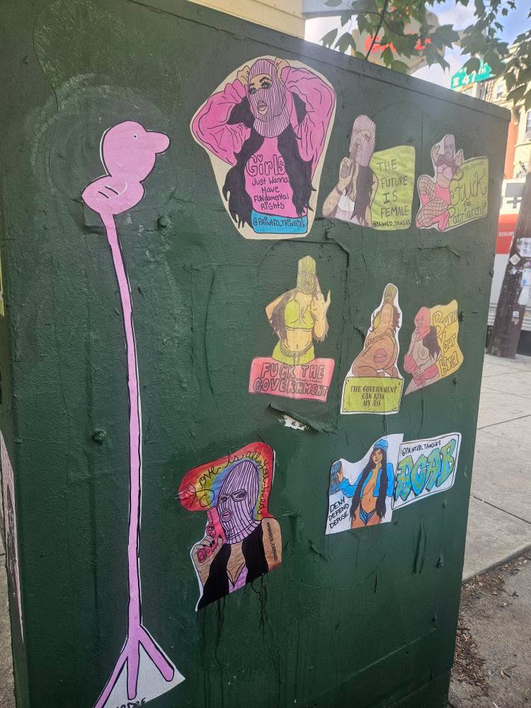 Street art by Alaina featuring hand-painted paste-ups and bold imagery centered on the female body, autonomy, and resistance in public space.